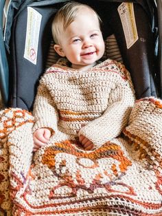 a little boy that is sitting in a stroller with a blanket over his head