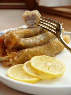 a fork is stuck into some fish on a plate with lemons and ketchup