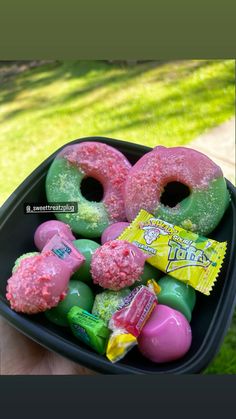 a black tray filled with donuts covered in pink and green sprinkles