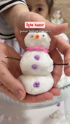 a person holding a snowman made out of cotton floss in front of a child's face