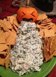 a green plate topped with chips and dip next to a jack - o'- lantern