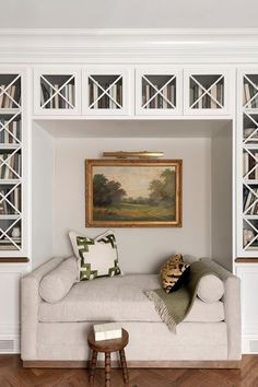 a living room with white bookcases and a couch in front of the bookshelf