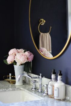 a white sink sitting under a mirror next to a faucet mounted on a wall