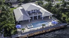 an aerial view of a large house with a pool and palm trees in the foreground