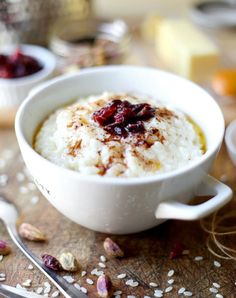 a white bowl filled with oatmeal and cranberries on top of a wooden table