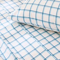 two pillows sitting next to each other on top of a white and blue checkered bed sheet