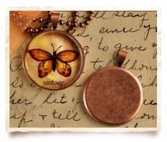 two necklaces with butterflies on them sitting on top of a piece of parchment paper