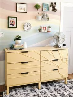 a yellow dresser sitting in front of a wall with pictures on it