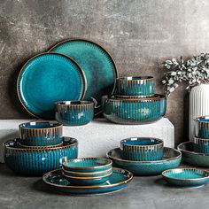 a table topped with plates and bowls next to a vase