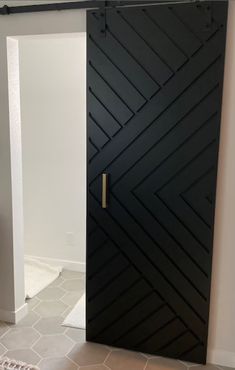 an open black door in a room with tile flooring and white walls on either side