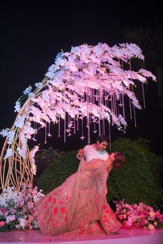 a man and woman kissing under a pink tree