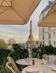 an outdoor dining area with tables, chairs and umbrellas in front of the eiffel tower