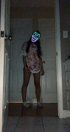 a woman standing in front of a door wearing a neon mask