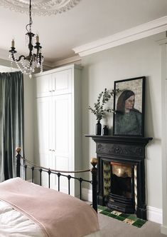 a bedroom with a bed, fireplace and chandelier