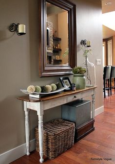 an entryway with a mirror, vases and baskets on the table