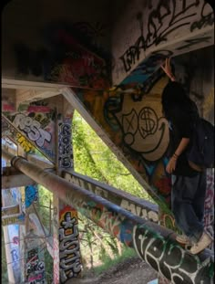 a man standing on the side of a bridge covered in grafitti and graffiti