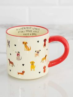 a red and white coffee mug with dogs on it sitting on a marble countertop