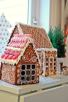 a gingerbread house with pink and white icing on it's roof, surrounded by other decorations