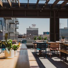 an outdoor dining area with wooden tables, chairs and plants on the table in front of it