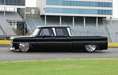 an old black pickup truck parked in front of a stadium