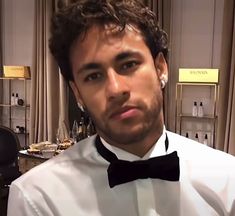 a man wearing a white shirt and black bow tie in front of a table with wine glasses