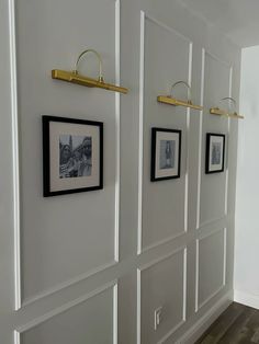 the wall is lined with white paneled walls and gold hooks on each side, along with black and white photos