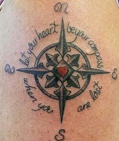 a compass tattoo on the back of a woman's shoulder with words written in cursive writing