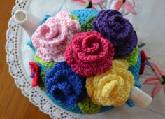 crocheted flowers are placed on top of a doily in the shape of a tea pot