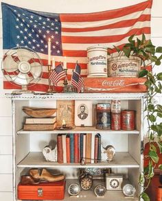 an american flag hanging on the side of a book shelf filled with books and other items