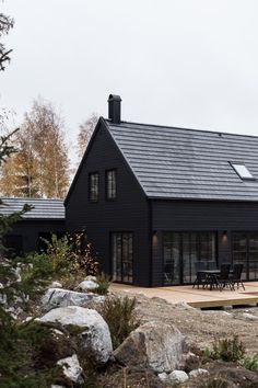 a black house surrounded by rocks and trees