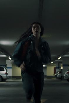 a woman with long hair running in a parking garage