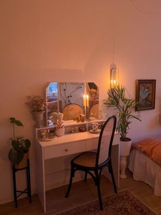 a bedroom with a bed, desk and mirror in it's corner next to a plant