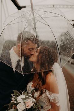 a bride and groom kissing under an umbrella