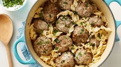 meatballs and noodles are in a blue pot with a wooden spoon on the side