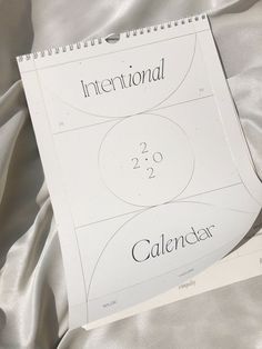 a calendar sitting on top of a bed covered in white sheets with the words international and 2 o'clock