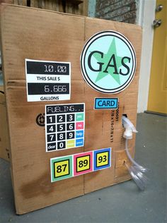 a cardboard box with gas prices on the front and side, attached to a wall