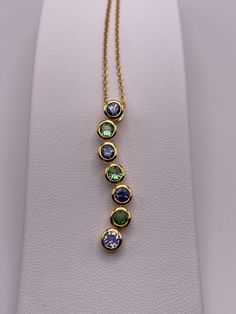 A journey pendant  is a piece of jewelry that symbolizes the twists & turns of a full lived life. This combination of Tanzanite & Tsavorite gemstones is our tribute to this beautiful sentiment. The vibrant complementary blue and green colors represent  the beauty of life. The well cut Tanzanites and Tsavorites are 3.5mm rounds  with a total carat weight of 1.05 carats. This beautiful pendant comes with a 16 inch chain featuring a lobster clasp. Bezel setting adds to the alluring look.Bezel setting adds to the alluring look. Check out our other Journey  Tanzanite pendant  as well. Visit our store Gem Tanzanite for more items. Journey Pendant, Tanzanite Pendant, The Beauty Of Life, Beauty Of Life, Natural Tanzanite, Bezel Setting, Pendant Necklaces, The Well, Green Colors