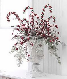 a vase filled with candy canes on top of a white table next to a window