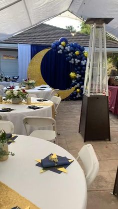 tables and chairs are set up under a white tent with blue curtains on the side