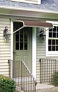 a white house with a brown awning on the front door and stairs leading up to it