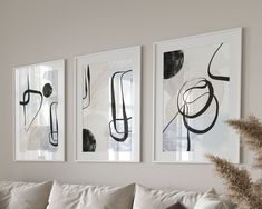 three black and white paintings hang on the wall above a couch in a living room