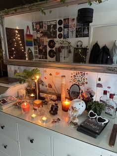 a counter with candles, pictures and other items on it in front of a mirror