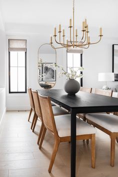 a dining room table with chairs and a vase on top of it in front of a mirror