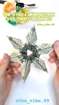 two hands holding up a dollar bill origami snowflake with the words how to fold a snowflake from 6 u s twenty dollar bills