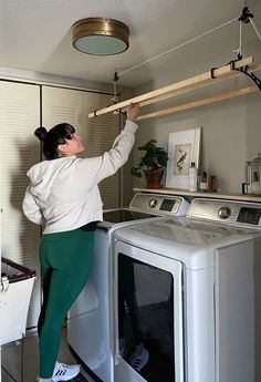 a woman standing on top of a dryer next to a washer and dryer