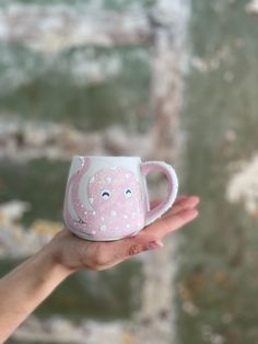 a hand holding a pink and white coffee cup with an octopus design on the inside