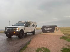 a white truck driving down a road next to a sign that says badland's national park