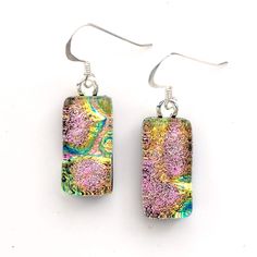 two square shaped earrings with pink and green designs on them, hanging from silver earwires