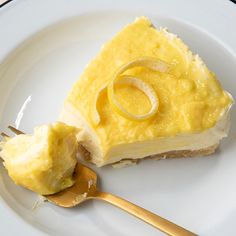 a piece of cake on a white plate with a gold spoon and fork next to it