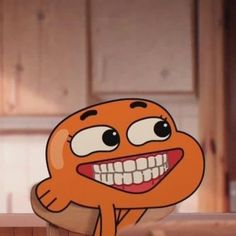 an orange cartoon character with big eyes and mouth wide open sitting on top of a wooden table